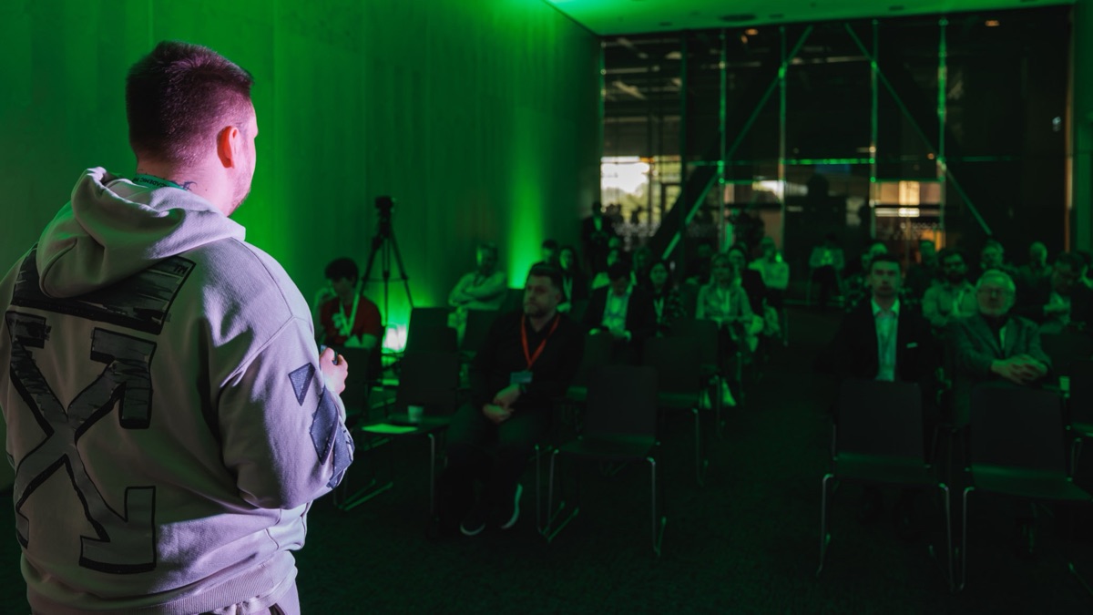 Jakub Lipiec podczas prelekcji na Health AI & CyberSec Summit, widok od strony sceny na publiczność